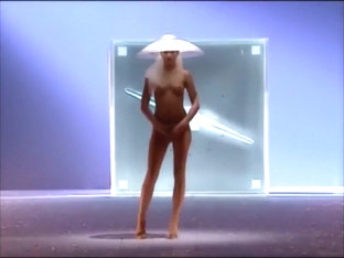 Seductive fashion model in a weird hat walks down the catwalk in the nude