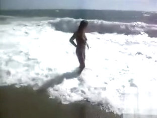 Busty brunette's lower part of a bikini drops as huge waves hit her