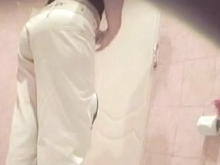 A Woman Wearing White Jeans Is Pissing In The Public Toilet