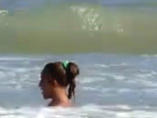 Topless legal age teenager playing at beach in water