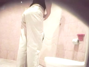 A Woman Wearing White Jeans Is Pissing In The Public Toilet