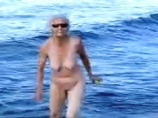 Naked Old Woman Playing And Having Fun On The Beach